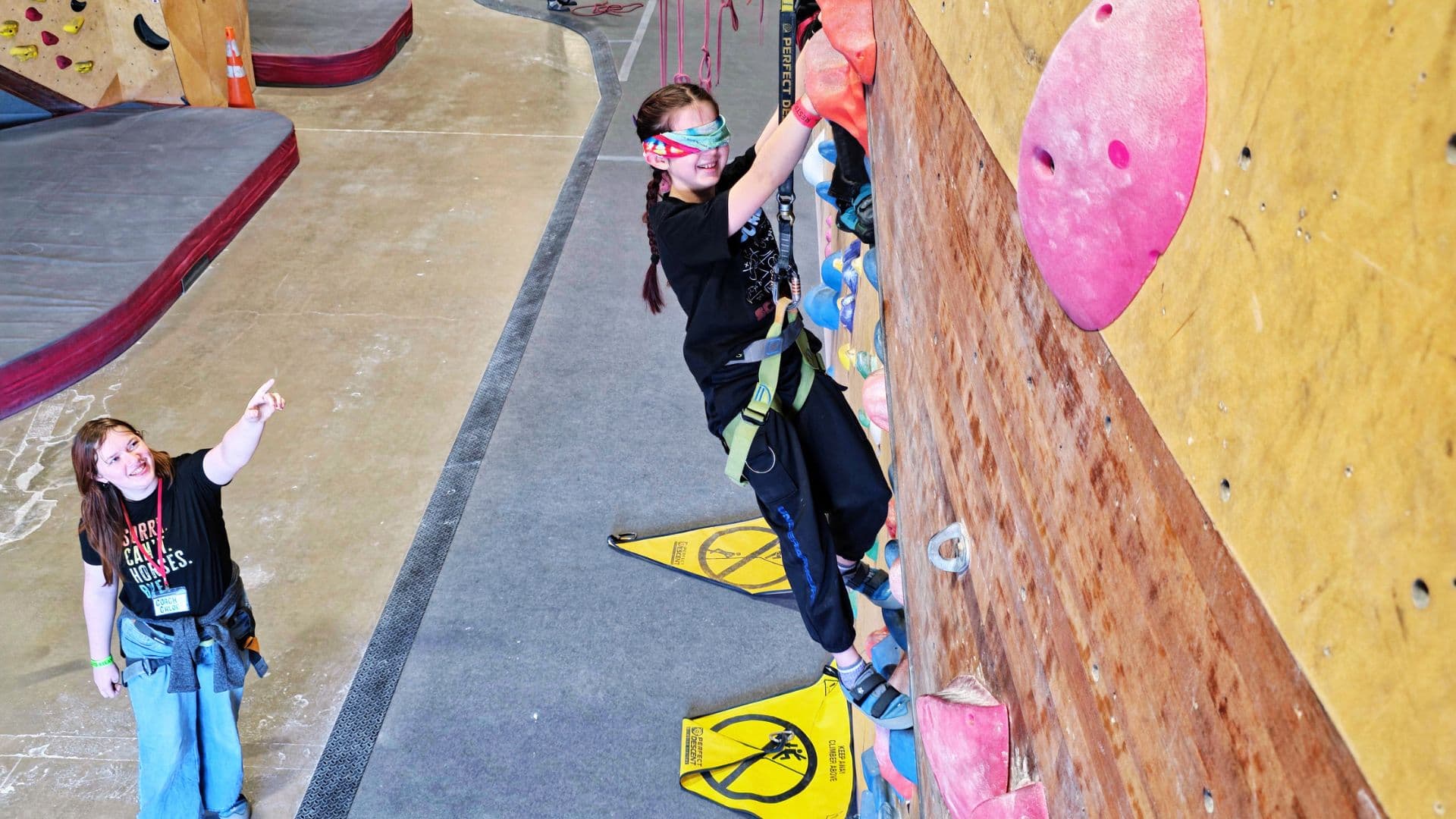Coach supporting a climber during a blindfolded climb